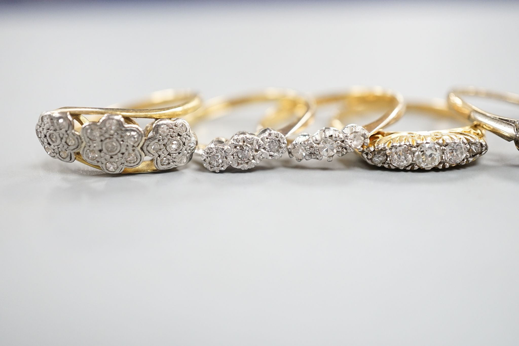 An early 20th century yellow metal and graduated five stone diamond set half hoop ring, size Q, gross 3.8 grams, three other 18ct and diamond chip set rings, gross 8 grams and a 9ct and diamond chip ring, gross 1.2 grams